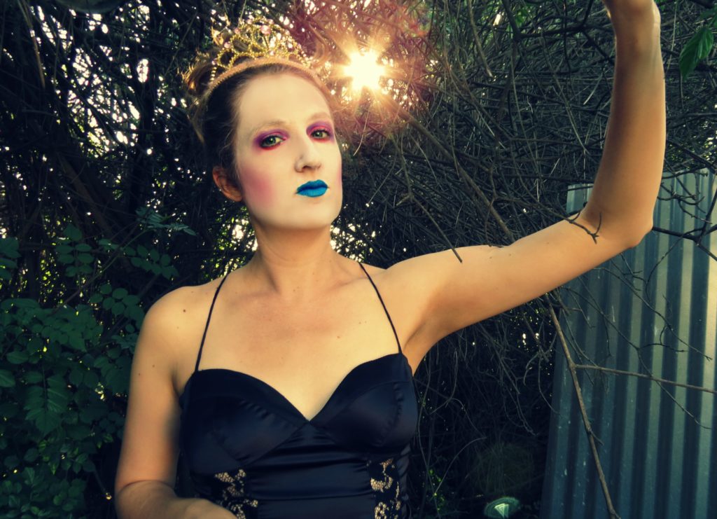 Catherine as Queen Mab in a black evening dress and blue lipstick.