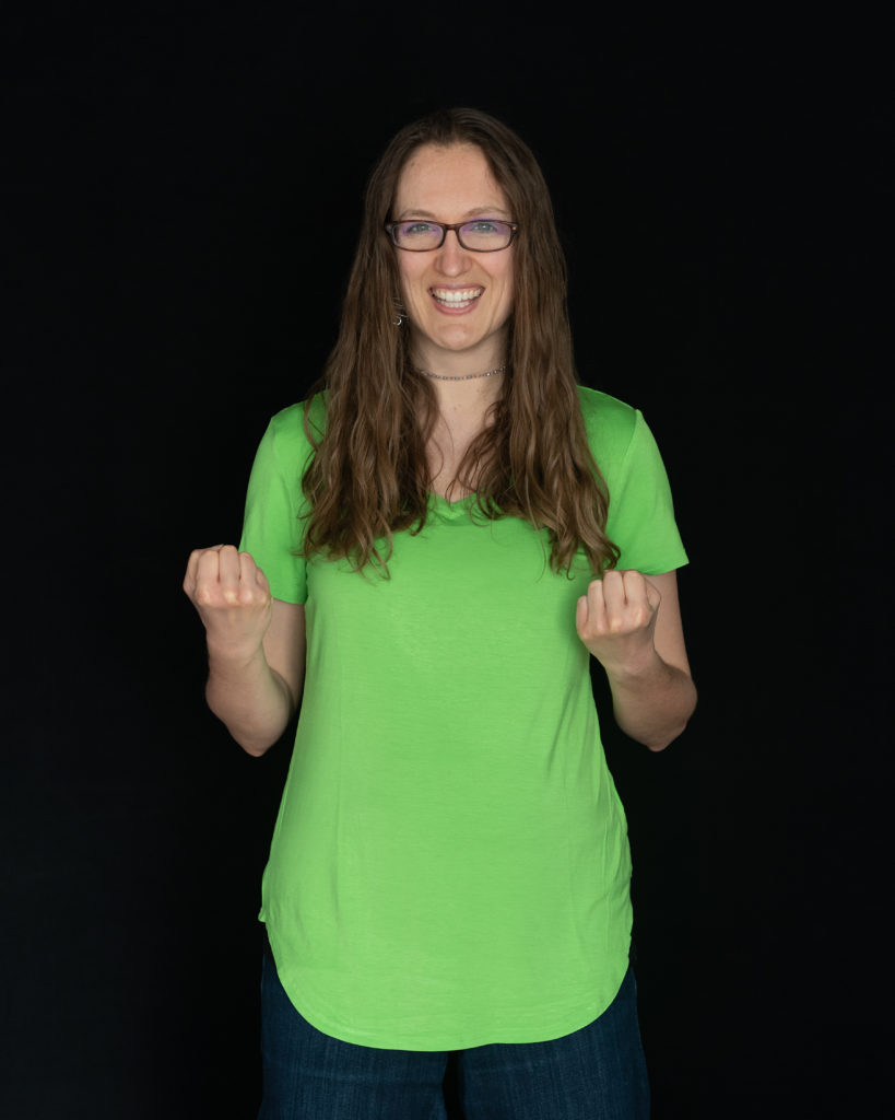 An awkward white lady in a green shirt makes a "yes" gesture with her hands